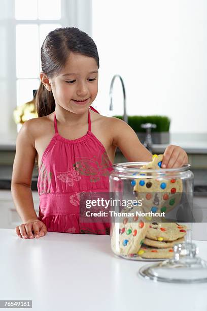 girl (4-6) reaching into cookie jar on kitchen counter - child cookie jar stock pictures, royalty-free photos & images