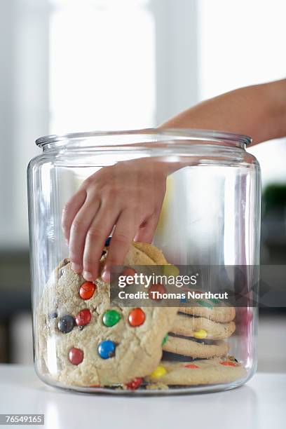 girl (4-6) reaching into cookie jar, close-up - pot met koekjes stockfoto's en -beelden