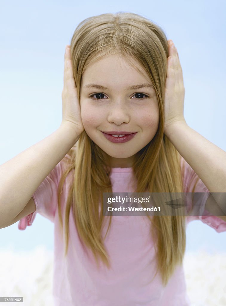 Girl (6-7), holding ears, portrait