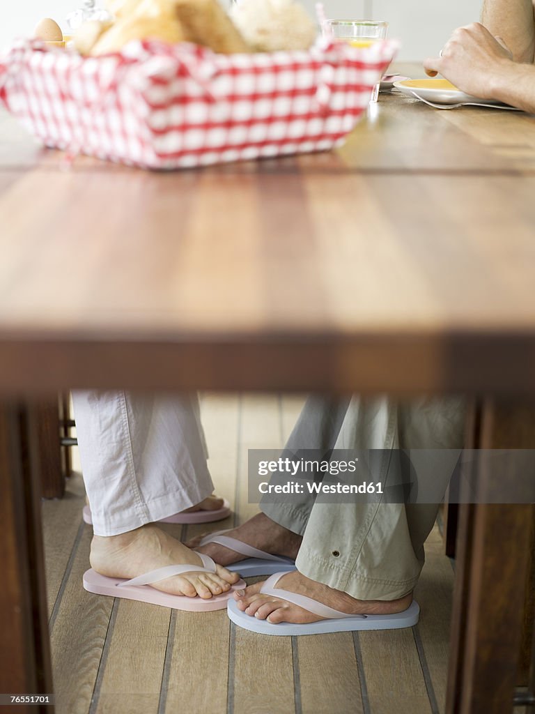 Couple touching feet under table