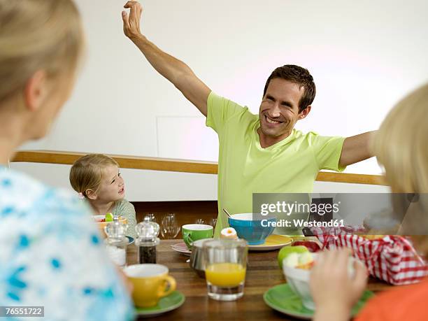 family at breakfast table - femme bras tendu cuillère photos et images de collection