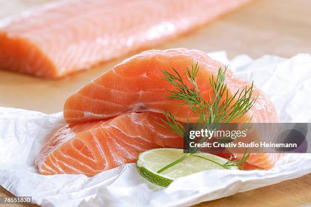 raw salmon on foil with slice of lemon, close-up - filleted stock pictures, royalty-free photos & images