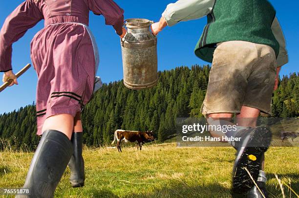 couple running, holding milk can, rear view - traditional clothing stock pictures, royalty-free photos & images