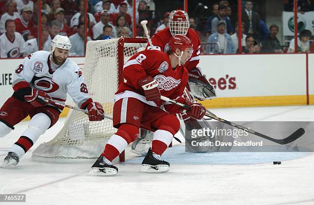 Center Igor Larionov of the Detroit Red Wings skates arouns his own net chased by left wing Erik Cole of the Carolina Hurricanes during game three of...