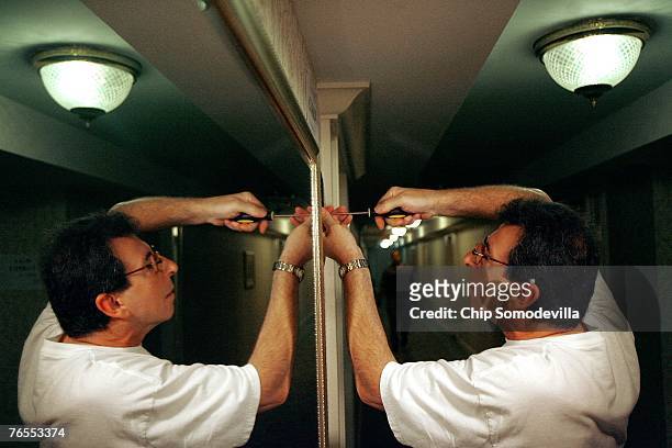 Former Secret Service agent and U.S. Department of Agriculture employee Dr. David Urso uses a screwdriver to remove a sign that points to the rooms...