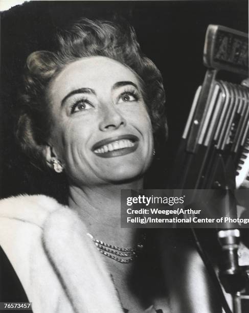 American actress Joan Crawford smiles from behind an Armed Forces Radio Saigon microphone, early 1960s.
