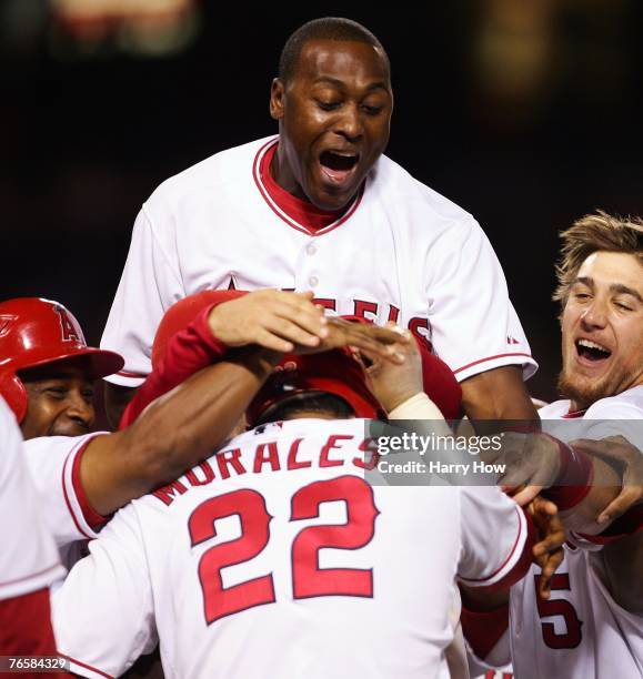 Gary Matthews Jr. #24, Jeff Mathis and Chone Figgins of the Los Angeles Angels celebrate the single of Kendry Morales to score the winning run and a...