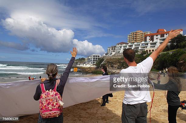 Protesters concerned about global warming unfurl a banner and wave in the direction of the spouses during 'the spouses lunch' held at Bondi Icebergs...