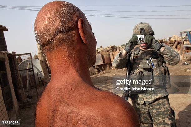 Army 1st Lt. William Cone from Des Moines, Iowa photographs a local resident for a data bank after searching for illegal weapons in his home...