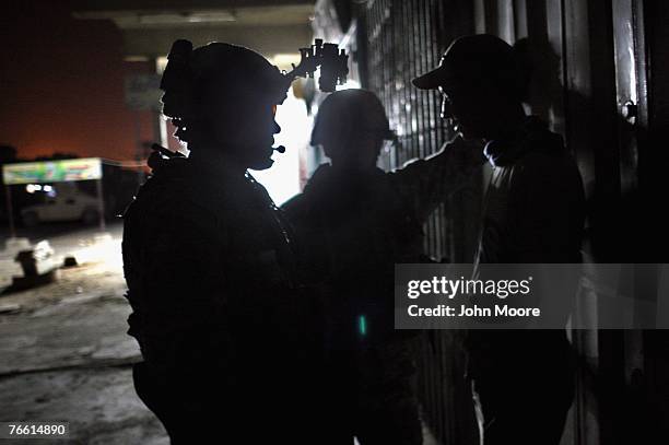 American forces question a man found driving his motorcycle after the 10pm citywide curfew September 9, 2007 in the Hurriyah neighborhood of Baghdad,...