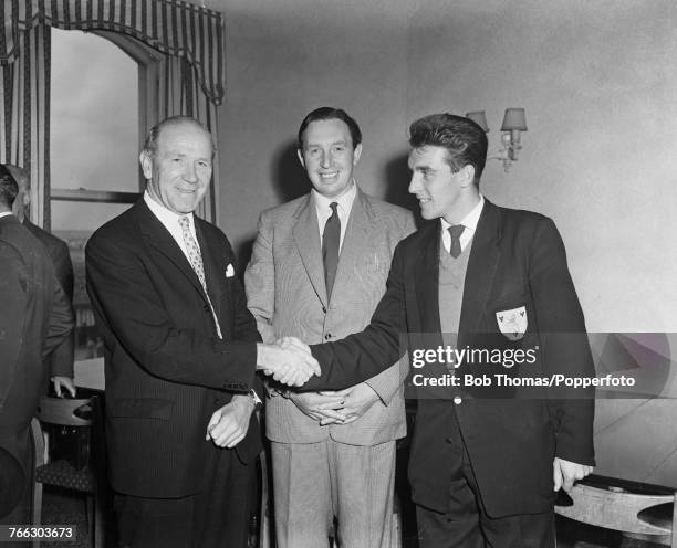 English footballer and former miner Bill Foulkes pictured on right shaking hands with manager Matt Busby as he signs as a player for Manchester...