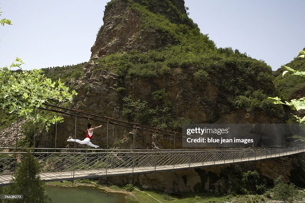 An athlete doing gymnastics on a hanging bridge.