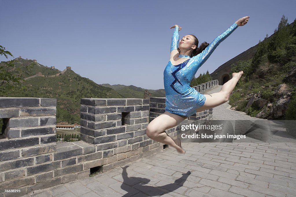 An athlete doing gymnastics on the Great Wall of China.