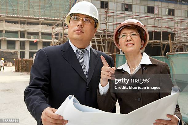 two investors discussing plans for a construction site. - falsework stock pictures, royalty-free photos & images