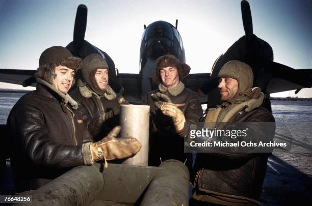 Crew members of a B-24 Liberator warm themselves in front of their plane at a United States Army Air Force base in December 1942 in Goose Bay,...