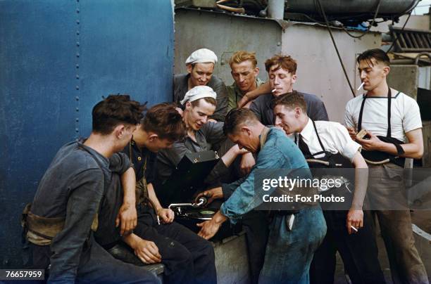 Members of the crew of a Royal Navy ship listen to a gramophone while on patrol in the Atlantic, circa 1943.