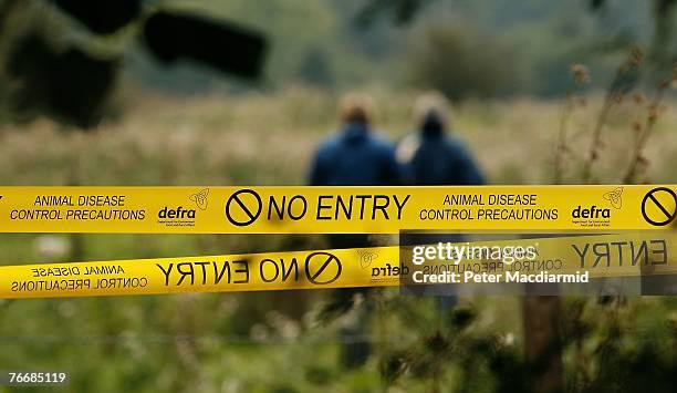 Government officials walk near signs warning of an outbreak of Foot and Mouth disease at farmland on September 12, 2007 near Egham, England. This new...
