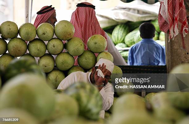 Saudi man hides his face from the camera as other men sample watermelon at Otaiga market in Riyadh, 12 September 2007, a day before the start of the...