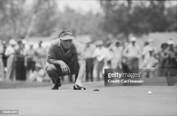 American golfer Arnold Palmer strategically crouches down as he lines up a shot at the Cherry Hills Country Club during the United States Open...