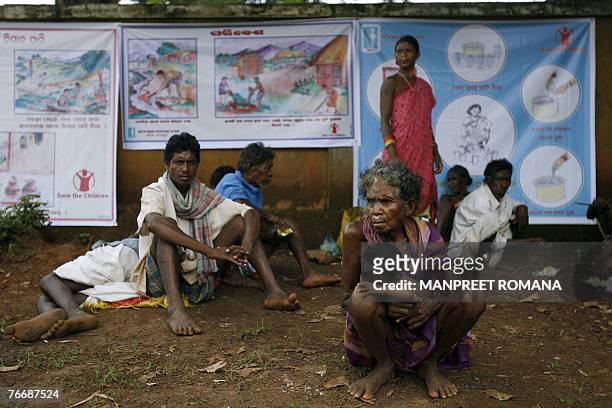 An Indian family sit in front of awareness posters put up on the wall to educate the public about water borne diseases outside a hospital in...