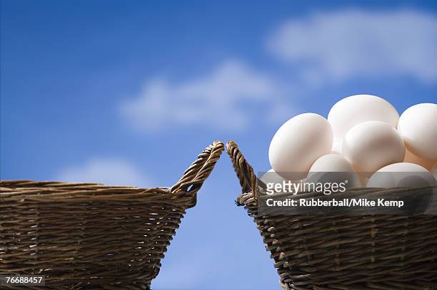 one empty basket and one basket filled with eggs outdoors with blue sky - eggs in basket stock pictures, royalty-free photos & images