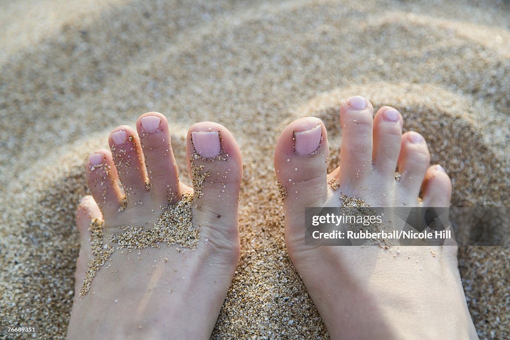Close-up of toes in sand
