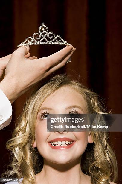 man placing crown on girl's head - beauty pageant crown stock-fotos und bilder