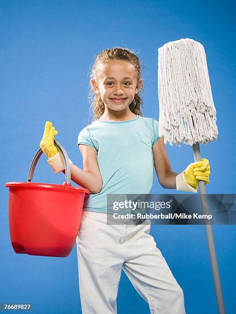 girl holding mop and bucket with rubber gloves smiling - kids with cleaning rubber gloves stock-fotos und bilder