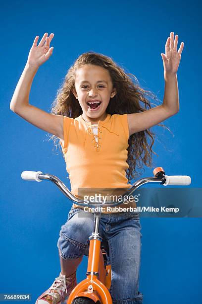 girl riding orange bicycle with no hands laughing - freihändiges fahrradfahren stock-fotos und bilder