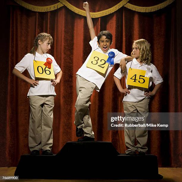 three children on stage at winner's podium with ribbons smiling - tweede plaats stockfoto's en -beelden