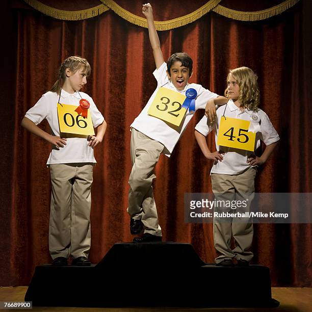 three children on stage at winner's podium with ribbons smiling - second best stock pictures, royalty-free photos & images