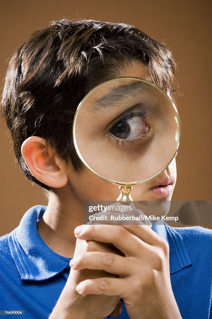 Boy holding magnifying glass to eye