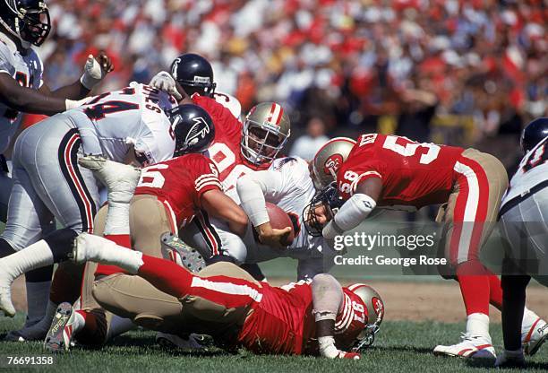 Linebacker Todd Kelly, defensive end Martin Harrison and Dennis Brown of the San Francisco 49ers sack Atlanta Falcons quarterback Bobby Hebert during...