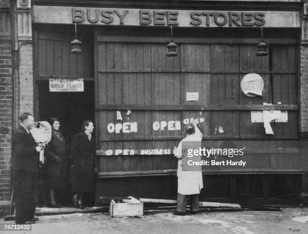 Shopkeeper declares his establishment open for business after an air raid on the East End of London during the Blitz, 28th September 1940. Original...
