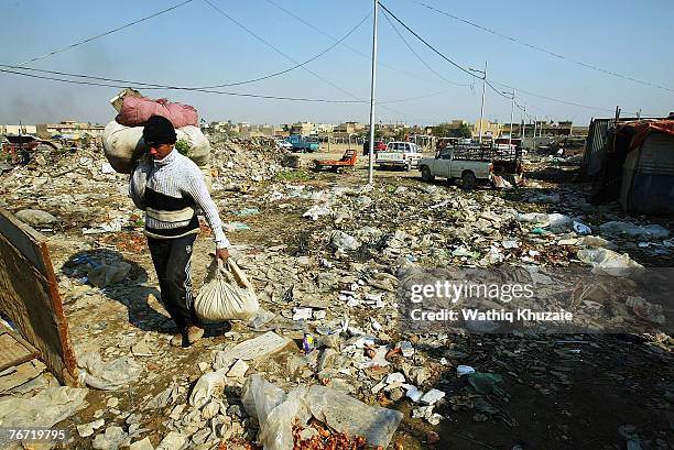 An Iraqi man walks near a pile of trash on February 14, 2007 in the street of Baghdad, Iraq.