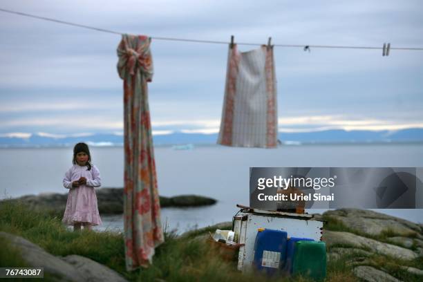 An inuit girl stands at her back yard, August 27 in the village of Ilimanaq, Greenland. Even though the disappearing ice cap could lead to higher sea...