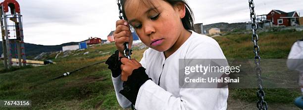 An inuit girl sits on a swing, in the village of Ilimanaq, august 27 Greenland. Even though the disappearing ice cap could lead to higher sea levels...