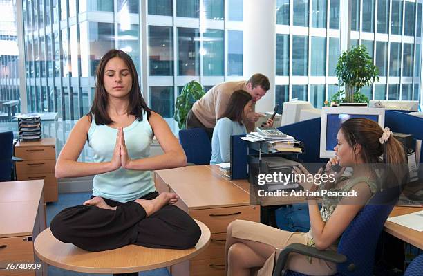 businesswoman in yoga position on table in busy office - international day four stock pictures, royalty-free photos & images