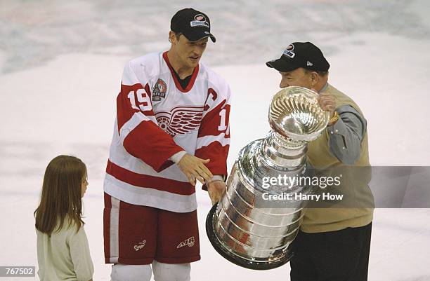Steve Yzerman of the Detroit Red Wings with daughter Isabella by his side hand the Stanley Cup over to Head Coach Scotty Bowman after defeating the...