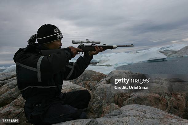 Arne Lange, a 39-year-old Inuit fisherman takes aim at a seal from an island, August 26, 2007 near his home town of Ilimanaq, Greenland. Lange, who...