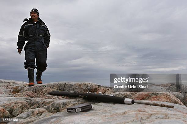 Arne Lange, a 39-year-old Inuit fisherman walks towards his rifle as he hunts seals from an island, August 26, 2007 near his home village of...