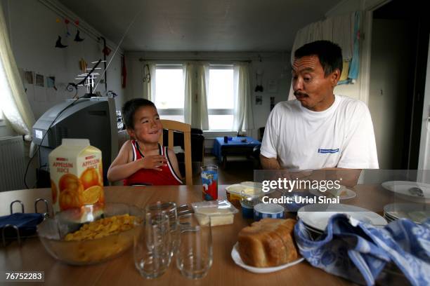 Arne Lange, a 39-year-old Inuit fisherman, eats breakfast with his five-year-old son Angut Rosbach August 27, 2007 in the village of Ilimanaq,...