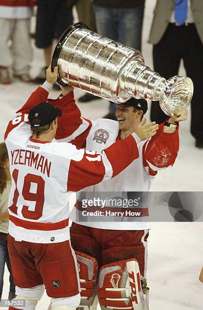 Steve Yzerman of the Detroit Red Wings hands the Stanley Cup off to Dominik Hasek as he raises it over his head after defeating the Carolina...