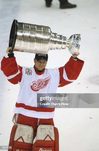 Manny Legace of the Detroit Red Wings raises the Stanley Cup after defeating the Carolina Hurricanes in game five of the NHL Stanley Cup Finals on...