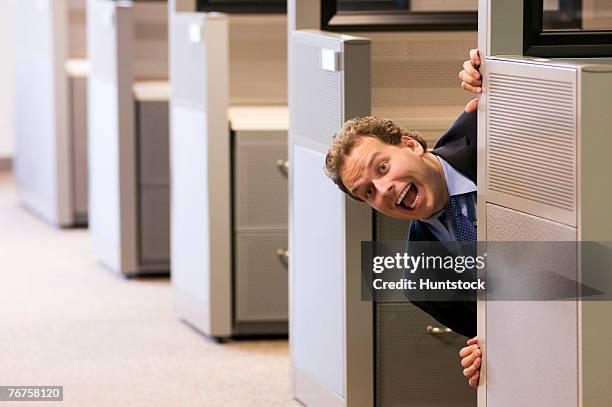 businessman looking out of his cubicle making funny face - peeking cubicle stock pictures, royalty-free photos & images