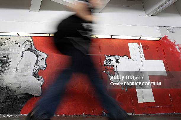 Child passes in front of a graffiti showing on the left the Swiss minister Christoph Blocher, member of the Swiss People's Party represented as a...