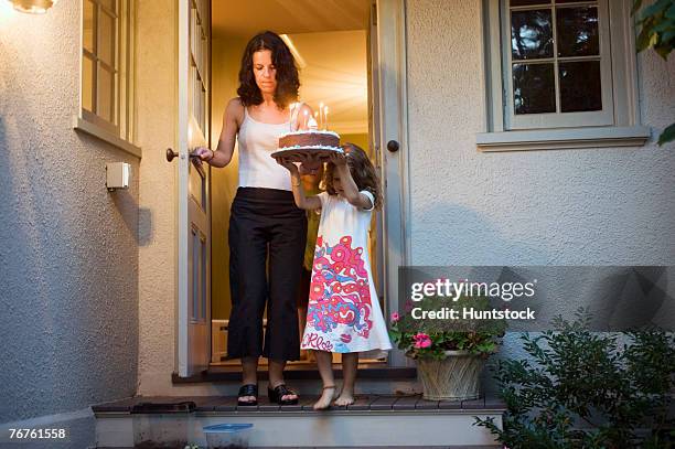 mother and daughter in doorway with birthday cake - holding birthday cake stock pictures, royalty-free photos & images