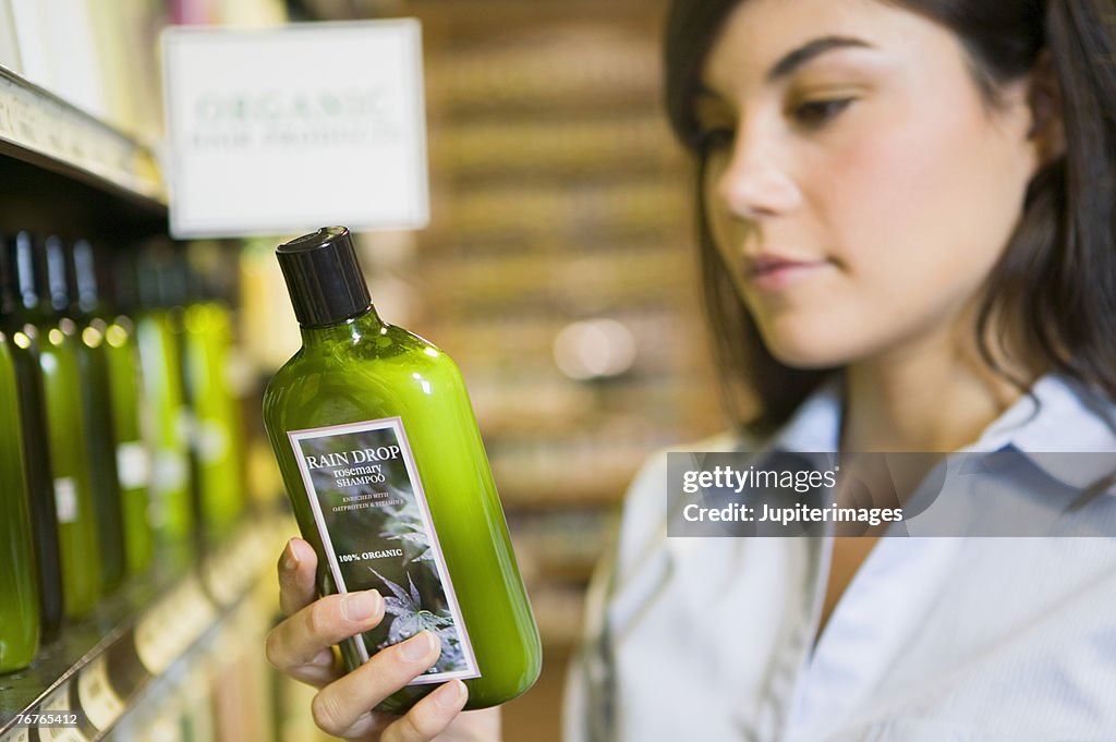 Woman reading label of organic shampoo