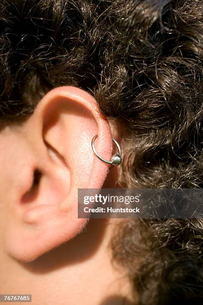 close-up of ear with cartilage earring - ear piercing stock-fotos und bilder