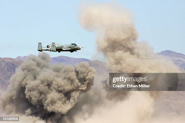 An A-10 Thunderbolt fires rockets as it flies by smoke rising from destroyed targets during a U.S. Air Force firepower demonstration at the Nevada...